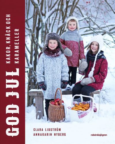 Tre barn poserar ute i snön. Framför sig har de en korg med lussebullar och en korg med äpplen.