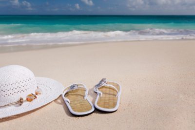 Hatt och sandaler på en strand